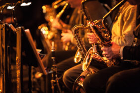A candid view along the saxophone section of a big band in concert.